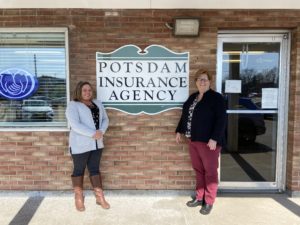 Markel and Amy smiling and standing in front of Potsdam Insurance Agency storefront.